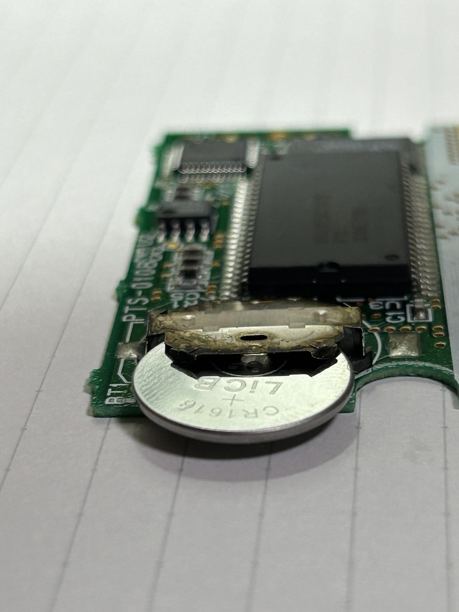 プラス面を上にした新品CR1616を電池ホルダーへ差し込んでいる状態